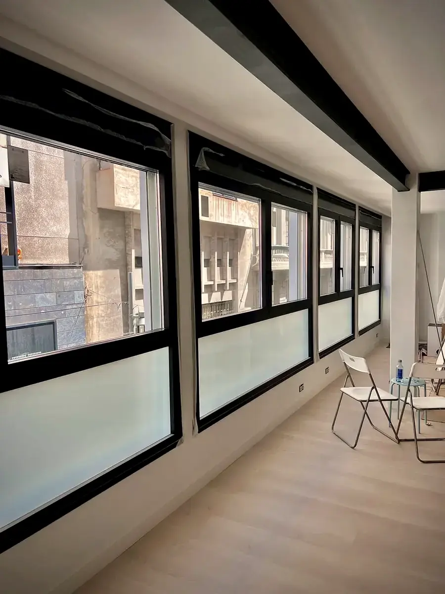 Hilera de ventanas de aluminio con vidrio traslúcido en el interior de un local