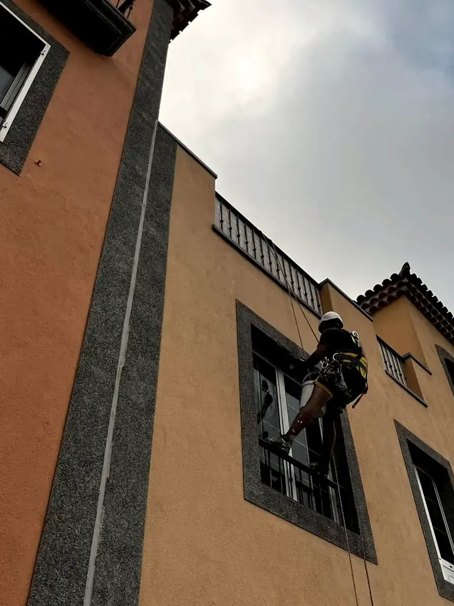 Operario de GSP Servicios descolgado por cuerda trabajando en la fachada de un edificio
