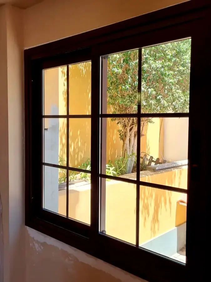 Ventana corredera de aluminio imitación madera con cuarterones recién instalada en una vivienda